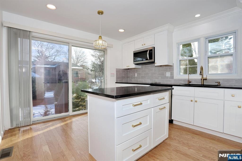a kitchen with granite countertop white cabinets and a large window