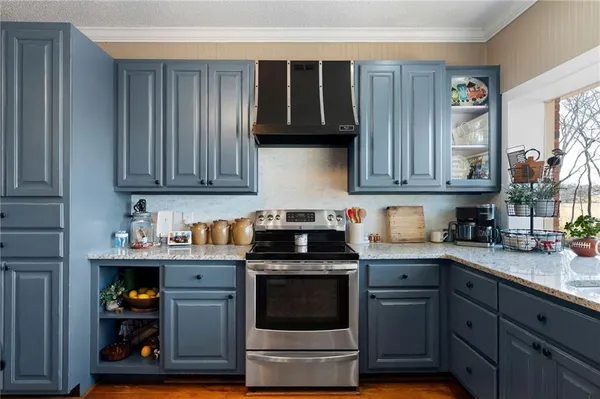a kitchen with a stove a sink a kitchen island with wooden cabinets and chandelier