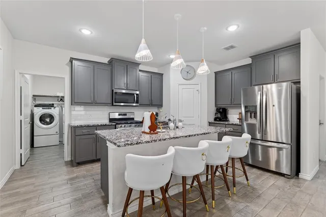 a kitchen with kitchen island granite countertop a sink a stove a oven a dining table and chairs