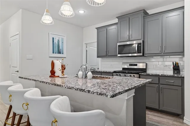 a kitchen with stainless steel appliances granite countertop a sink a stove and a refrigerator