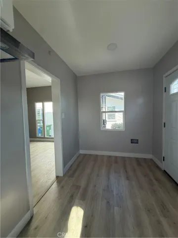 an empty room with wooden floor cabinet and windows