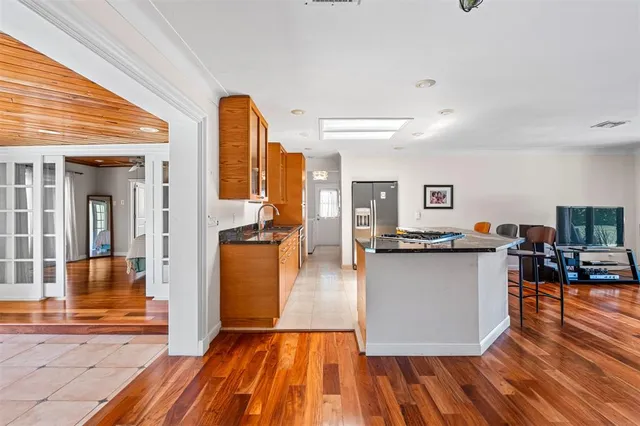 a living room with stainless steel appliances granite countertop furniture wooden floor and a kitchen view