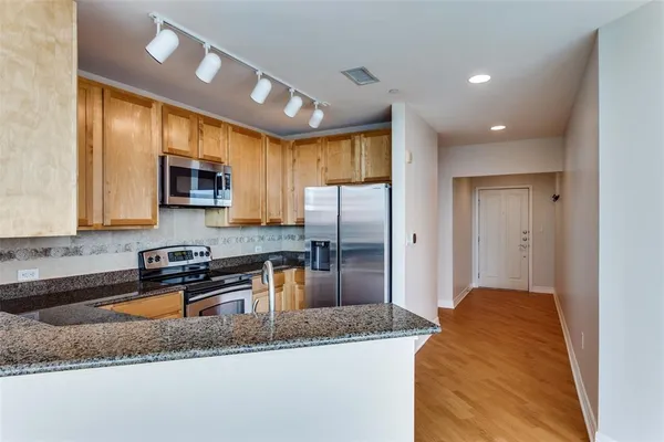 a kitchen with stainless steel appliances granite countertop a sink a stove and a refrigerator