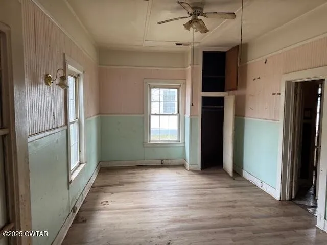 a view of empty room with wooden floor and fan