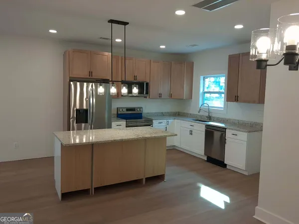 a kitchen with kitchen island granite countertop a sink cabinets and stainless steel appliances