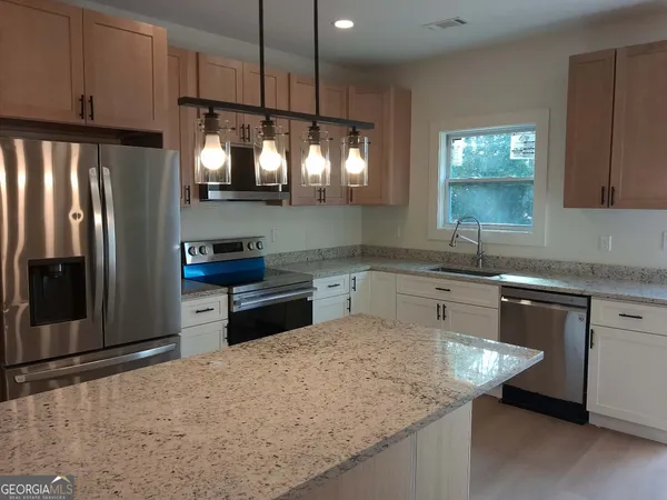 a kitchen with granite countertop a sink cabinets and stainless steel appliances