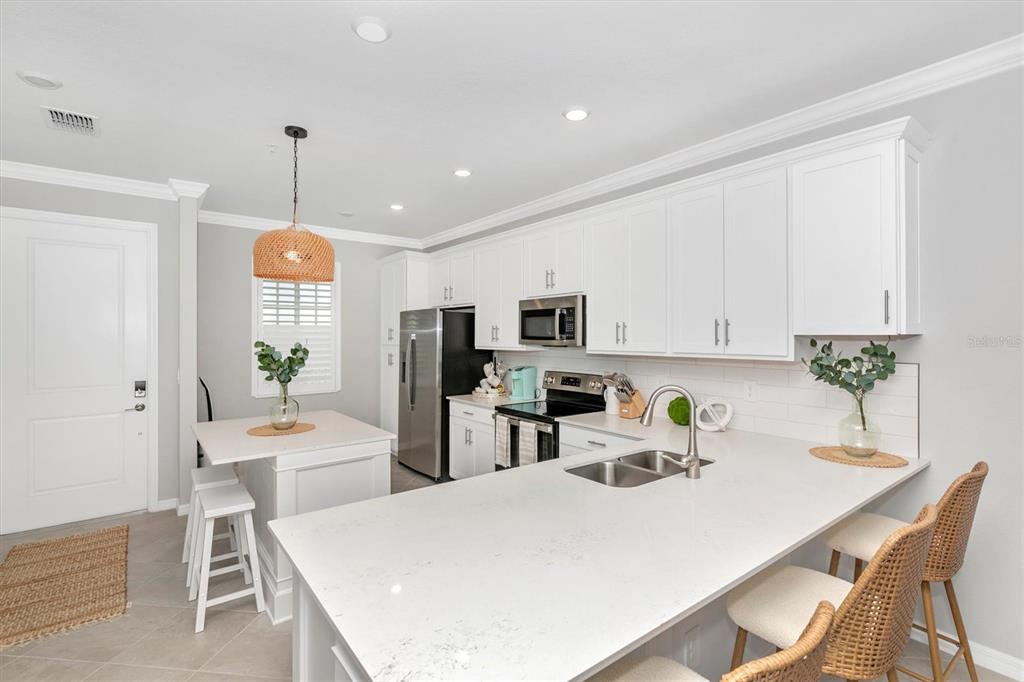 12280 Wellen Golf Street, Unit 403 Venice, FL 34293 - Photo 5 of 97 a kitchen with stainless steel appliances a white table and chairs in it