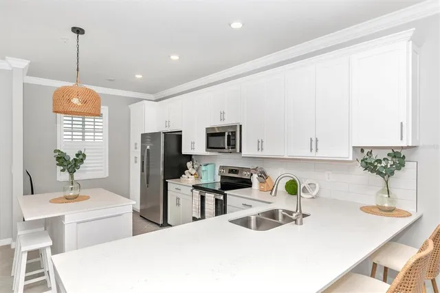 a kitchen with stainless steel appliances granite countertop a sink a stove a microwave a refrigerator and white cabinets