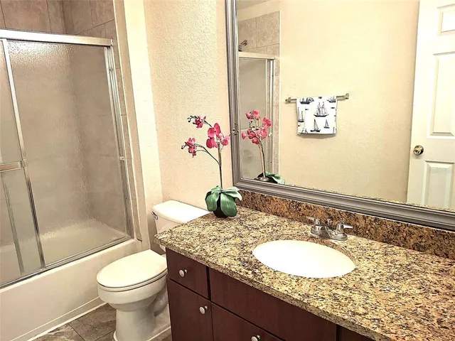 a bathroom with a granite countertop sink toilet and shower