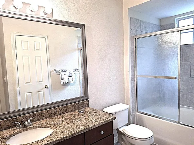 a bathroom with a granite countertop sink toilet and shower