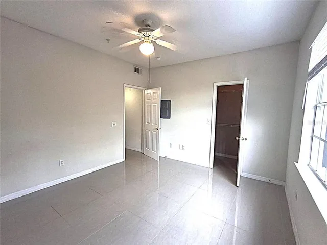 an empty room with fan and windows