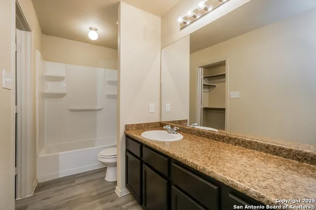 a bathroom with a granite countertop sink a toilet a mirror and shower