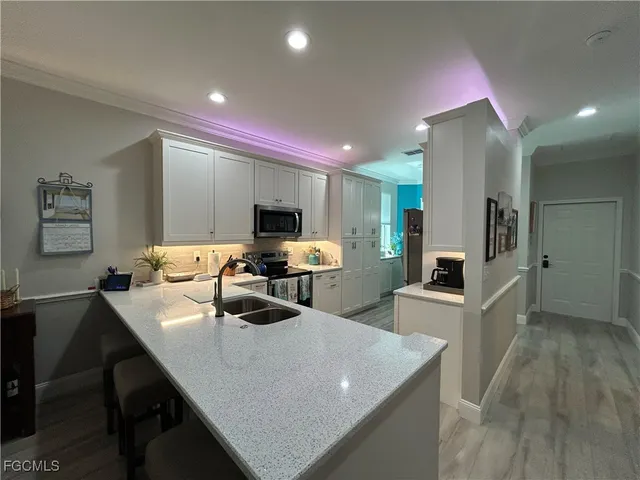 a large kitchen with sink a counter and chairs