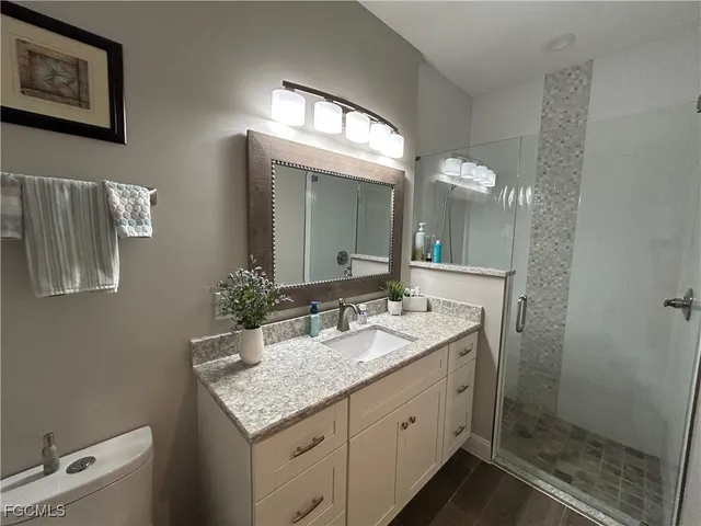 a bathroom with a granite countertop sink a large mirror and a shower