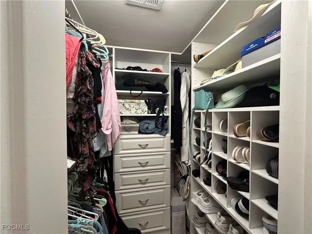 a view of walk in closet with clothes and shoes