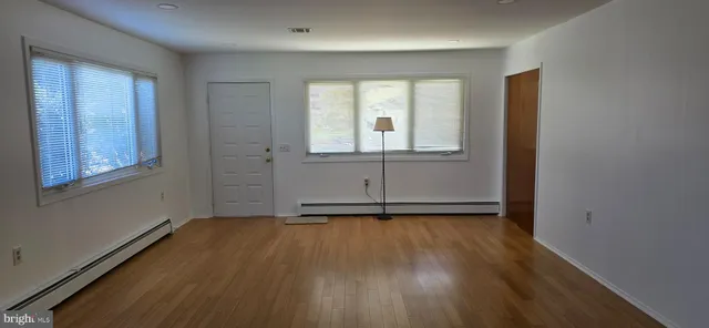 an empty room with wooden floor and windows