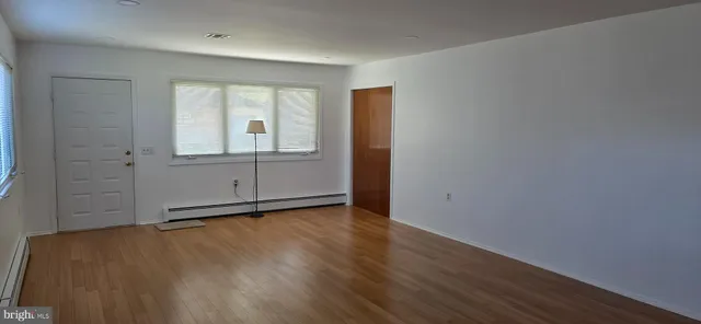 an empty room with wooden floor and window