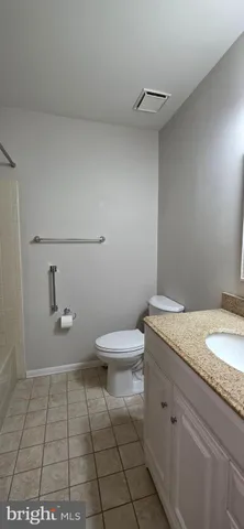 a bathroom with a granite countertop toilet and a sink