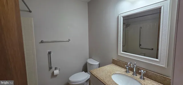 a bathroom with a granite countertop toilet sink and mirror