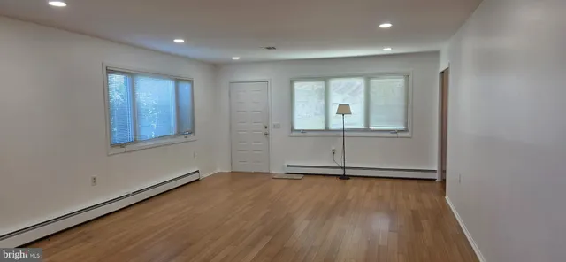 an empty room with wooden floor and windows