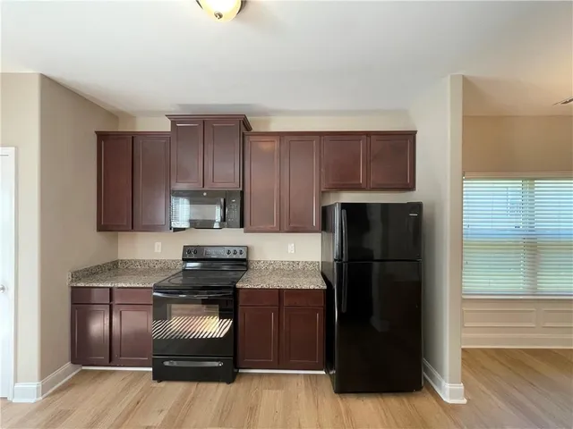 an empty room with wooden floor cabinet and windows