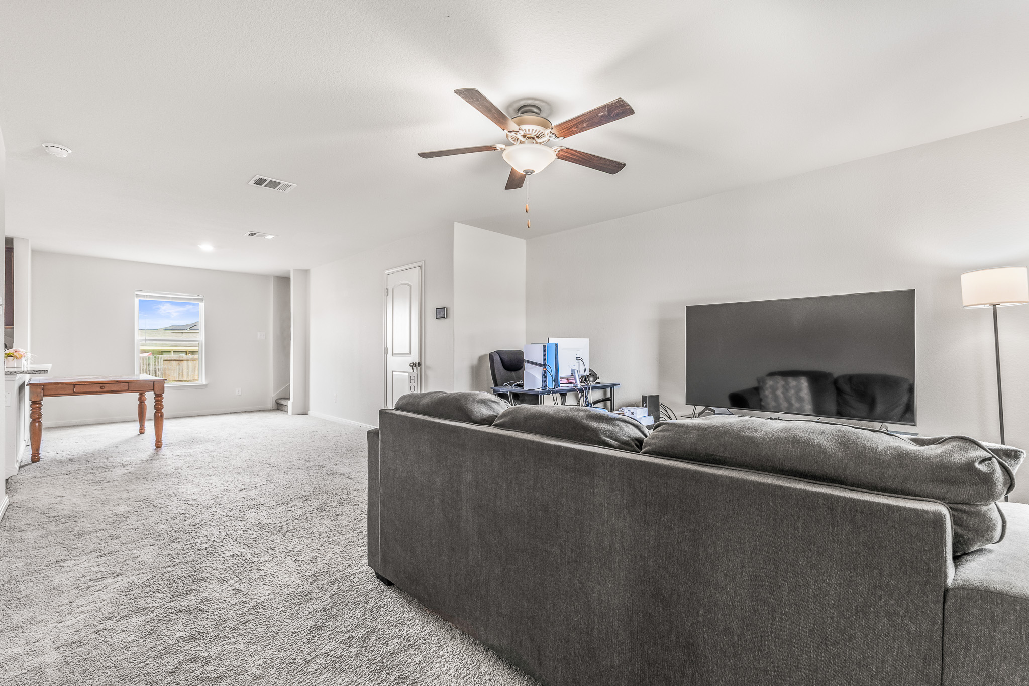 304 Hyacinth Way, Unit #7K Jarrell, TX 76537 - Photo 4 of 26 A versatile living space showcasing a ceiling fan and plush carpeting for comfort.