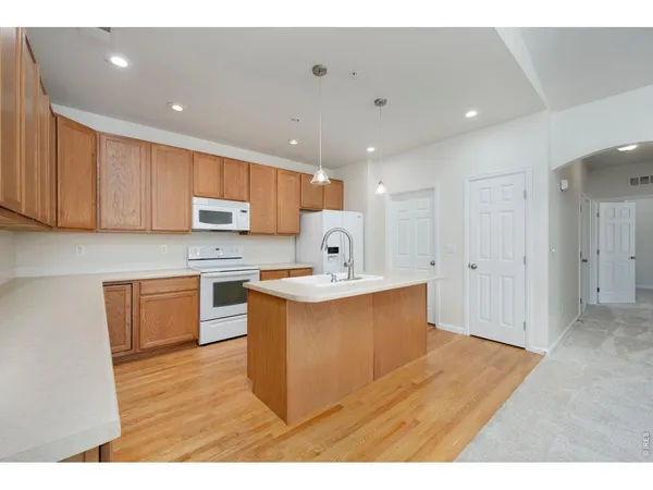 a large white kitchen with kitchen island a sink a stove a refrigerator and white cabinets