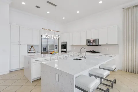 a kitchen with stainless steel appliances a white table chairs and a refrigerator