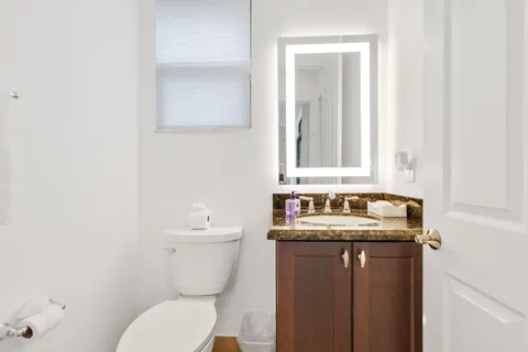 a bathroom with a granite countertop toilet sink and mirror