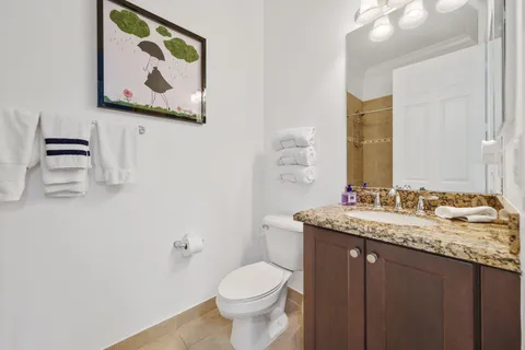 a bathroom with a granite countertop toilet sink and mirror