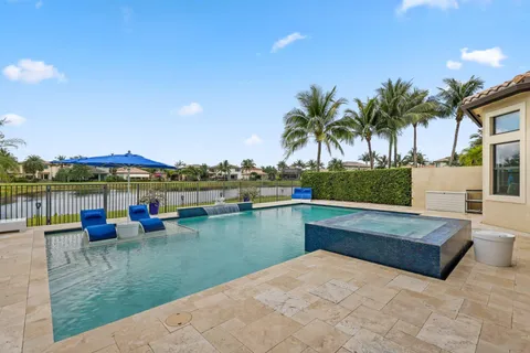 a view of a swimming pool with a yard and palm trees