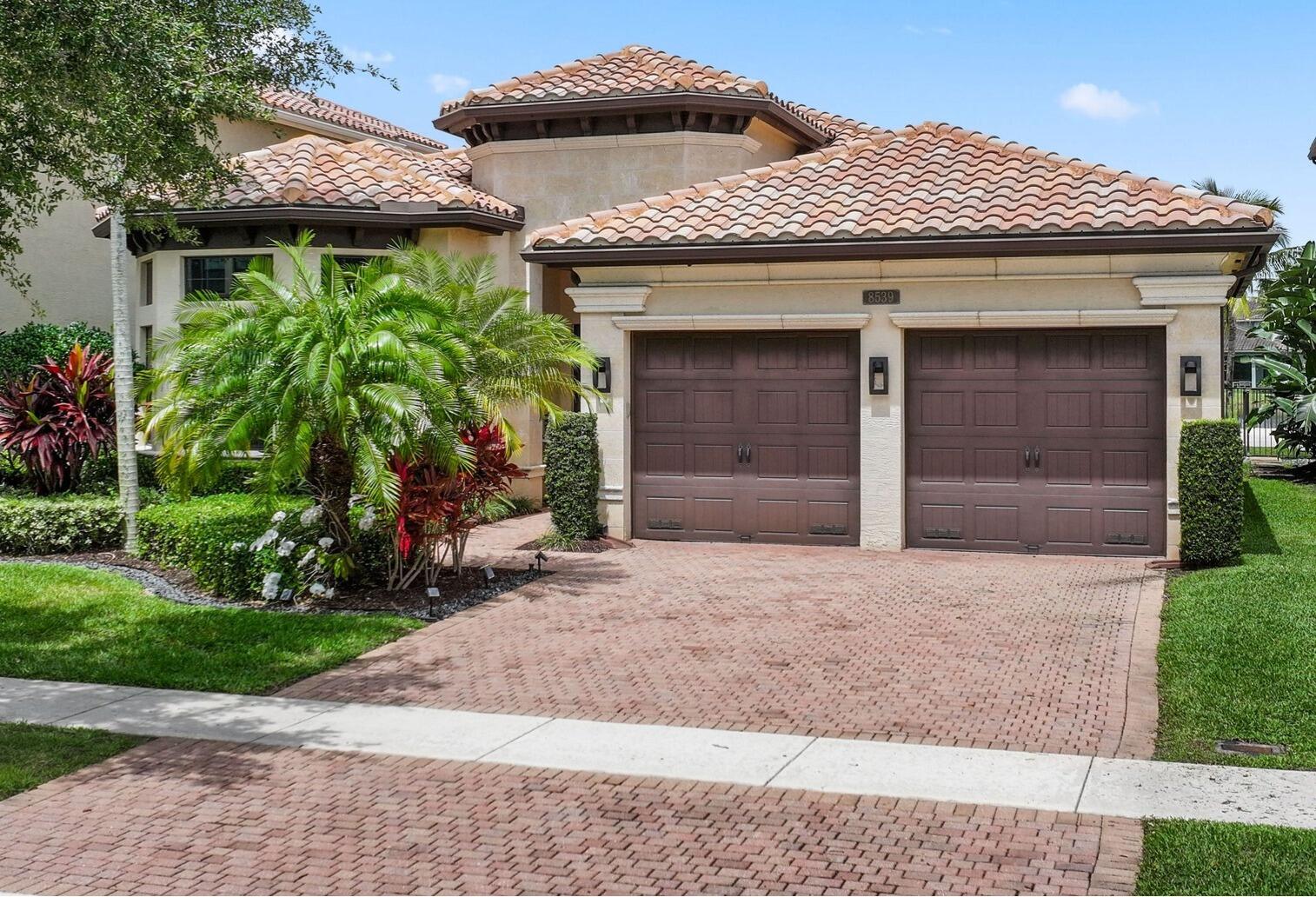 8539 Lewis River Road Delray Beach, FL 33446 - Photo 4 of 49 a front view of a house with a garden and plants
