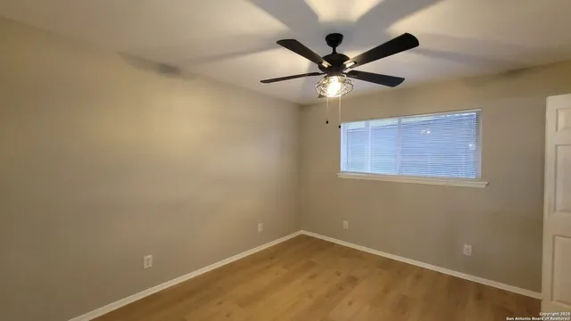 an empty room with a window and a fan