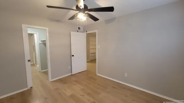 an empty room with closet and a chandelier fan