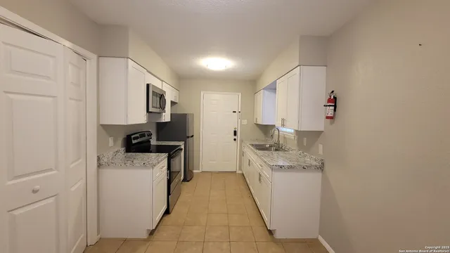 a kitchen with a sink a stove top oven and stainless steel appliances