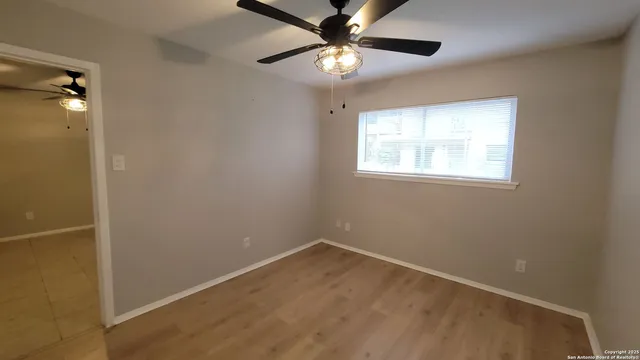 an empty room with a window and a fan