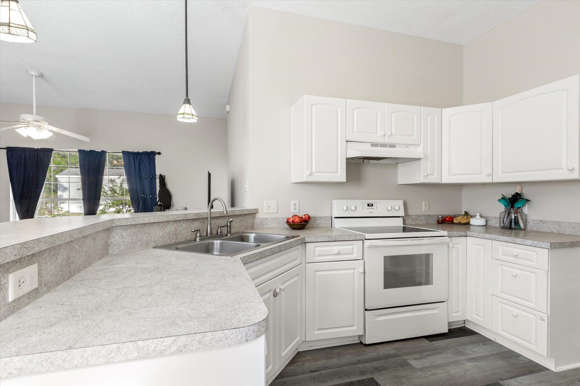 3372 4th Street Elkton, FL 32033 - Photo 11 of 36 Kitchen with white electric range oven, white cabinetry, pendant lighting, light countertops, and under cabinet range hood