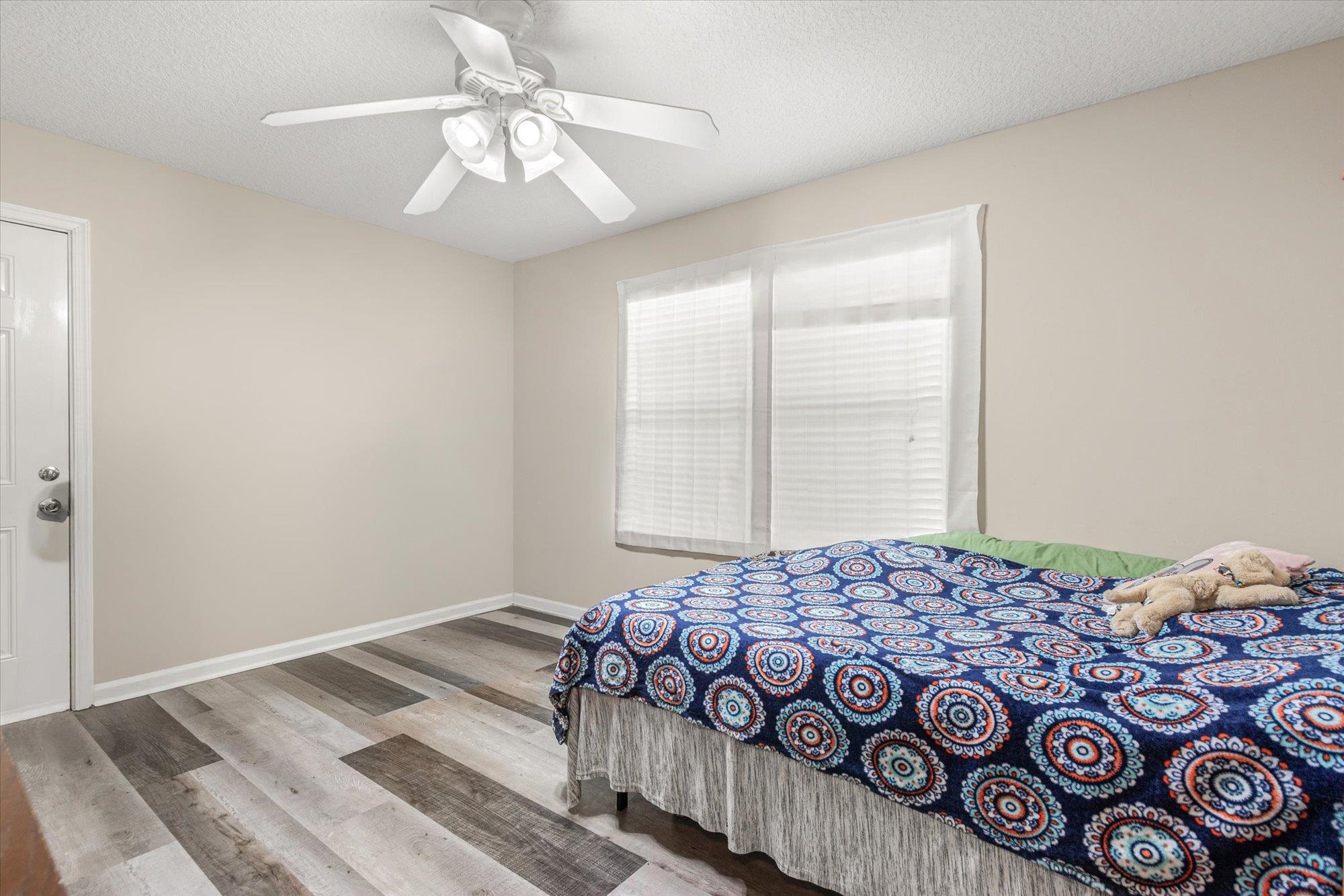 3372 4th Street Elkton, FL 32033 - Photo 16 of 36 Bedroom featuring a textured ceiling, light wood-style floors, and a ceiling fan