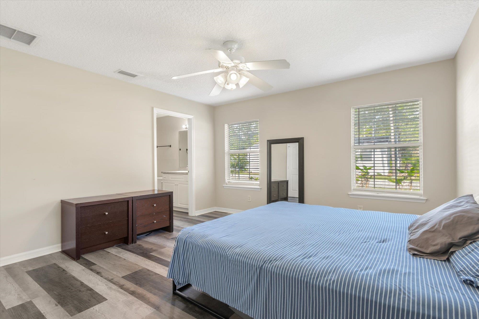 3372 4th Street Elkton, FL 32033 - Photo 19 of 36 Bedroom featuring wood finished floors, a textured ceiling, ceiling fan, and ensuite bath