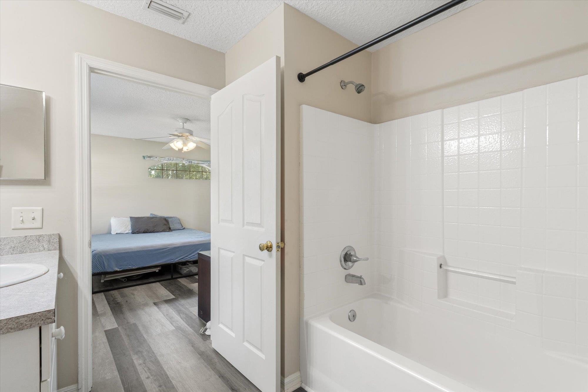 3372 4th Street Elkton, FL 32033 - Photo 22 of 36 Ensuite bathroom with a textured ceiling, vanity, shower / washtub combination, dark wood-style flooring, and ceiling fan