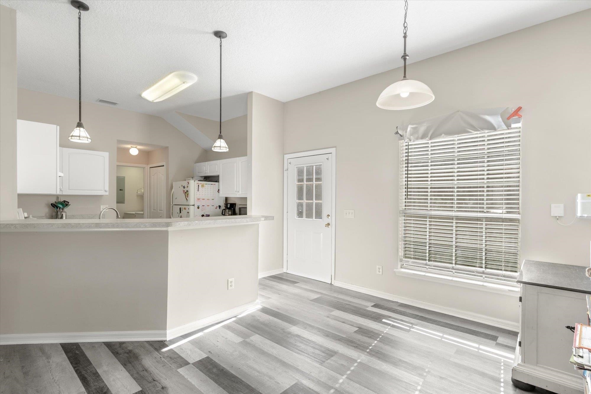 3372 4th Street Elkton, FL 32033 - Photo 6 of 36 Kitchen with white cabinetry, decorative light fixtures, freestanding refrigerator, vaulted ceiling, and light wood-style flooring