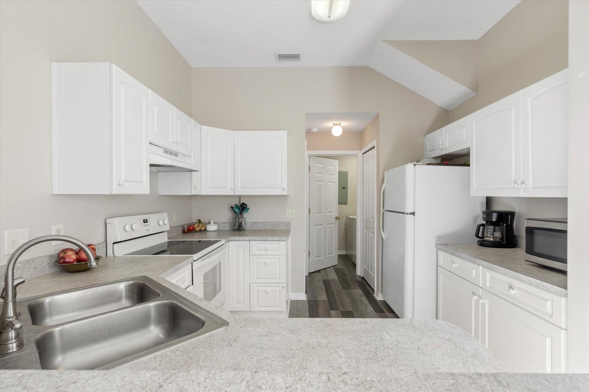 3372 4th Street Elkton, FL 32033 - Photo 9 of 36 Kitchen with white appliances, dark wood-style flooring, white cabinetry, and under cabinet range hood