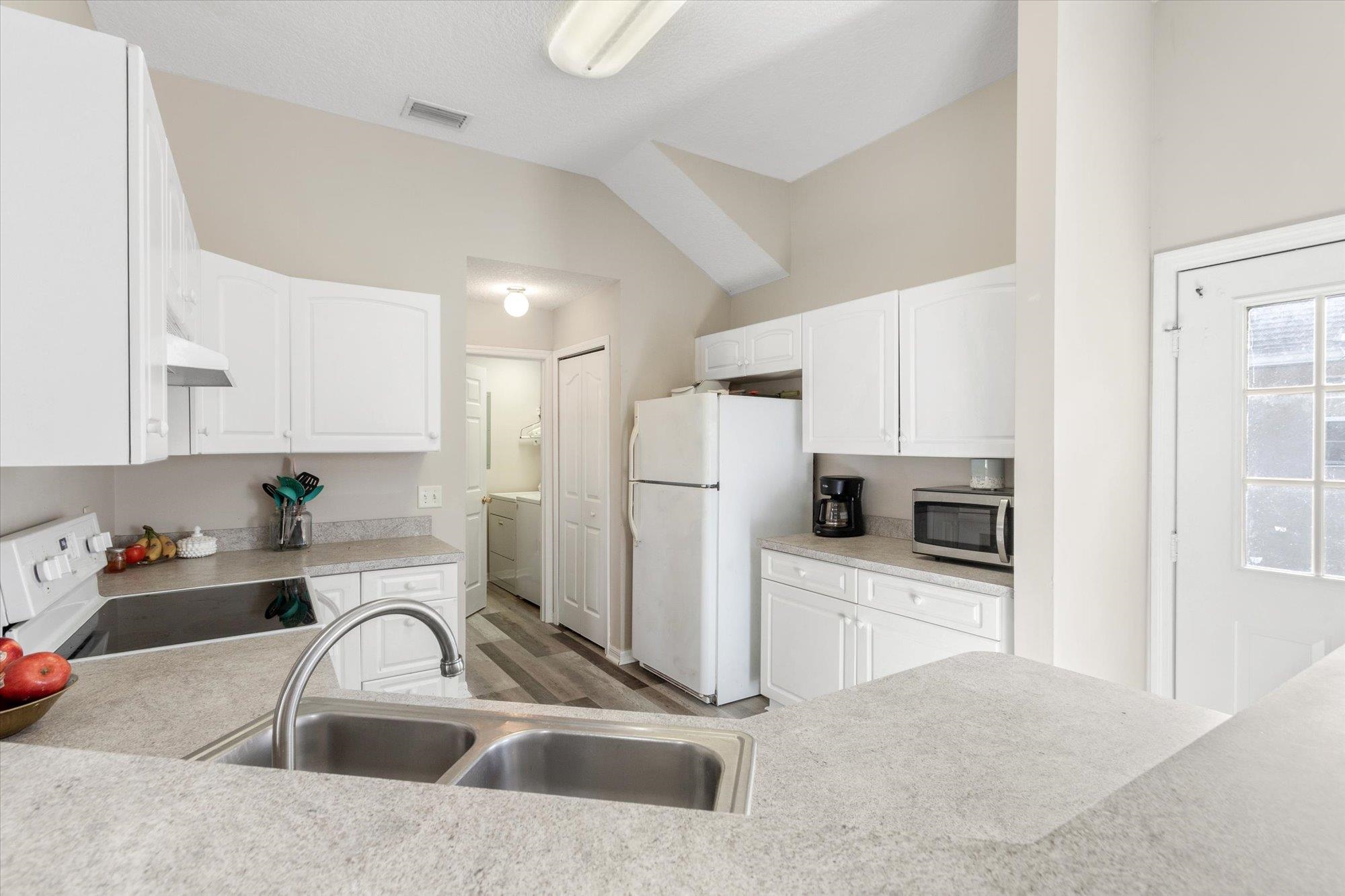 3372 4th Street Elkton, FL 32033 - Photo 10 of 36 Kitchen with white cabinetry, light countertops, white appliances, light wood-style floors, and washing machine and dryer