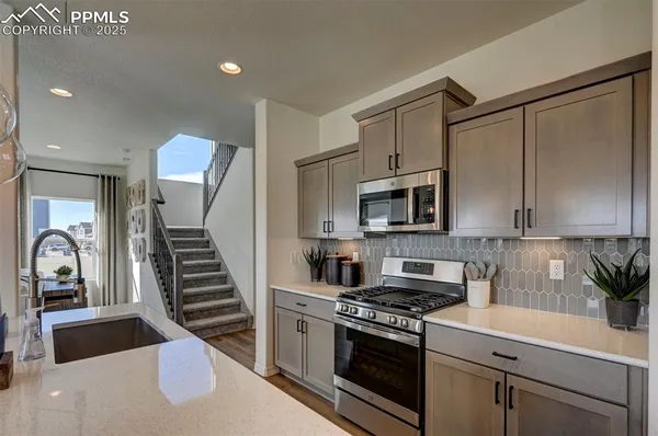a kitchen with stainless steel appliances granite countertop a stove a sink and a microwave