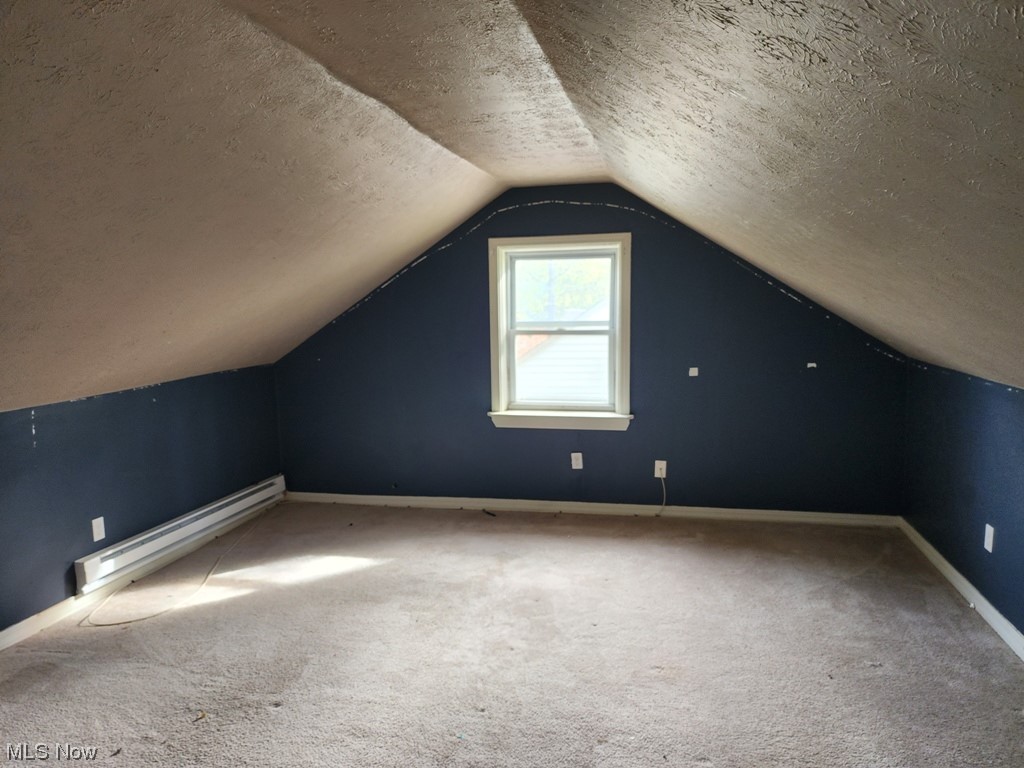 3602 Silsby Road University Heights, OH 44118 - Photo 11 of 19 Additional living space with vaulted ceiling, a textured ceiling, a baseboard heating unit, and carpet flooring