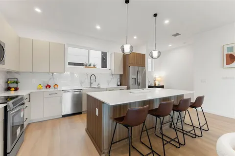 a kitchen with stainless steel appliances kitchen island a table chairs in it and white cabinets