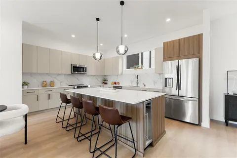 a kitchen with stainless steel appliances granite countertop a sink a stove a refrigerator and island with wooden floor
