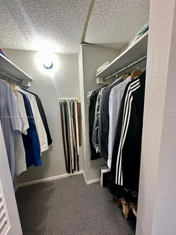 a view of walk in closet with clothes and shoes