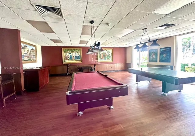 a room with pool table windows and wooden floor