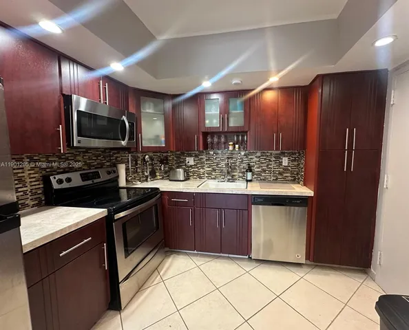 a kitchen with stainless steel appliances kitchen island granite countertop a stove refrigerator and cabinets